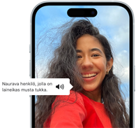 iPhone 15:ssä on näkyvillä VoiceOver-ilmoitus, jossa kuvataan valokuvaa seuraavasti: naurava henkilö, jolla on laineikas musta tukka